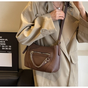 Detail of dark brown pebble leather tote bag with gold chain and decorative zipper pocket
