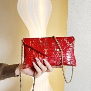 Detail of red envelope bag with gold chain and snake skin texture embossed leather