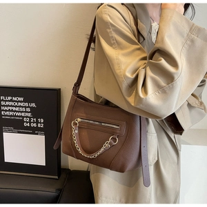 Detail of dark brown pebble leather tote bag with gold chain and front zipper pocket