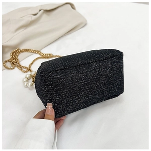 Detailed macro view of black sequin evening bag with gold chain and pearl handle accents