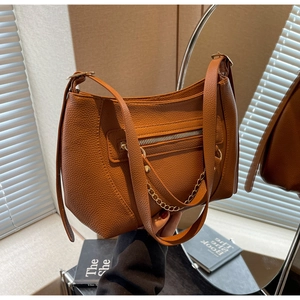 Close-up of brown litchi grain leather tote bag with gold chain and zipper detail