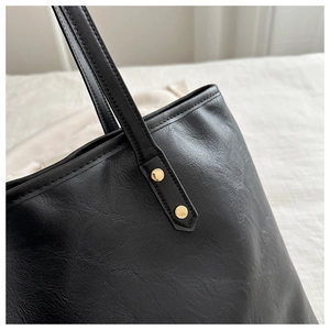Close-up of black PU leather tote bag with gold rivets and detailed stitching