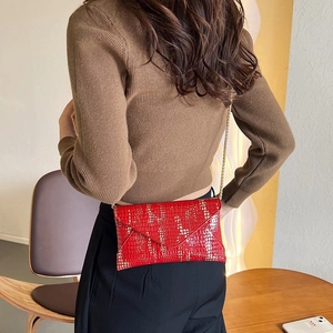 Detail shot of red glossy crocodile texture envelope bag with gold metal chain strap