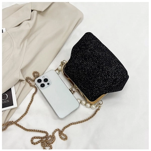 Detail view of black sequin evening bag with gold pearl chain next to a smartphone