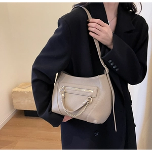 Detail of beige lychee textured leather tote with light gold chain and zipper pocket