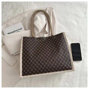 Dettaglio della borsa tote vintage a quadri con finiture in tela beige su sfondo bianco pulito