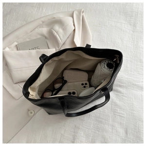 Top-down view of spacious black tote bag interior showing daily items and lining