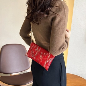 Detail of red embossed envelope chain bag with gold accents in a stylish setting
