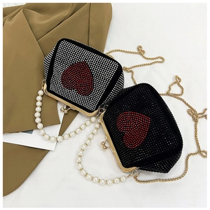Detail view of heart-shaped rhinestone evening bag with pearl handle and golden chain