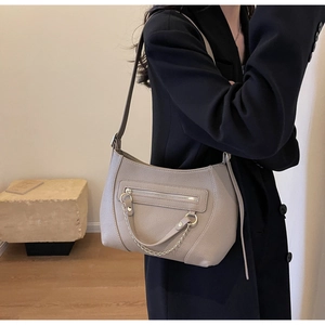 Detail of beige lychee texture leather shoulder bag with metal chain and zipper pocket