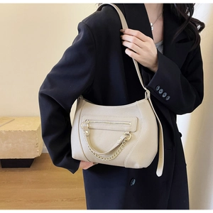 Detailed macro view of beige lychee texture faux leather bag with stylish gold chain detail