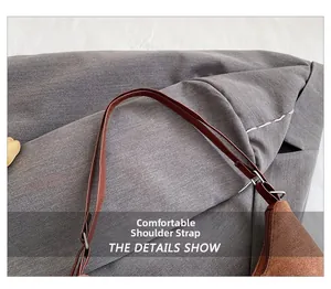 Detail view of adjustable brown suede shoulder strap with metal buckle on a tote bag