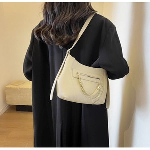 Close-up of cream crescent tote bag with pebble leather and gold chain detail