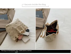 Detail view of beige woven bucket bag with floral embroidery and gold chain strap