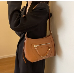Close-up of brown lychee pattern leather shoulder bag with golden chain and zip detail