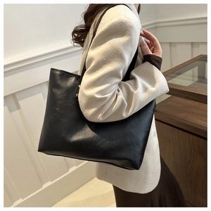 Detailed side view of minimalist black leather tote bag worn by a model for daily use