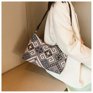 Détail de la broderie ethnique géométrique sur un sac sous l'aisselle avec sangle en cuir