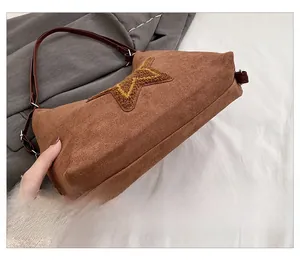 Detail of the brown suede tote bag bottom showing the star patch and metal strap rings