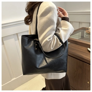 Modern black large tote bag in matte PU leather shown worn on the shoulder by a model