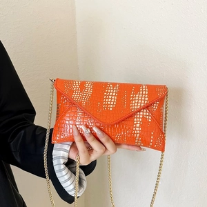 Detail of orange envelope clutch with crocodile texture and silver glitter chain strap