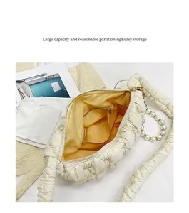 Detail view of cream ruched cloud bag featuring large capacity and elegant pearl handle