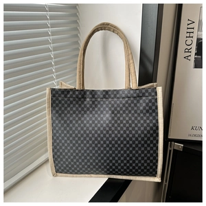 Dettaglio della borsa tote grigia a motivi geometrici con manici in tessuto beige al sole