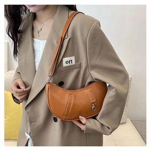Detail of orange-brown crescent bag with adjustable strap and metallic buckle decoration