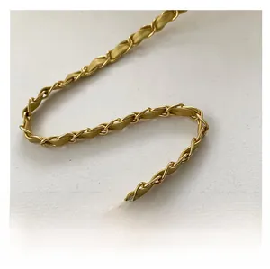 Detail of the elegant light gold metal chain interwoven with premium leather strap