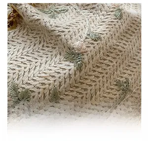 Detailed close-up of beige woven bucket bag with 3D floral embroidery and gold chain link