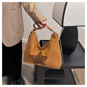 Detail of vintage brown suede shoulder bag featuring a dark star patch and metal chain strap