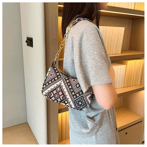 Détail d'un sac bohème tissé aux motifs géométriques colorés et bandoulière chaîne dorée