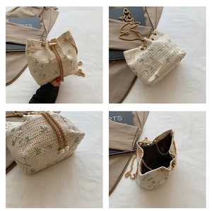 Close-up of woven bucket bag with floral embroidery, drawstring closure and chain strap