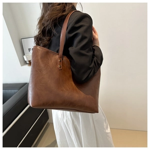 Detailed view of brown leather tote bag with vintage texture and reinforced metal rivets