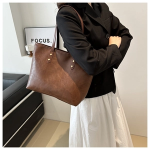 Close-up of brown tote bag featuring vintage leather texture and gold stud details