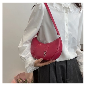 Detail showing fuchsia crescent shoulder bag with silver buckle on model with white shirt