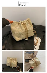 Detail of khaki straw bucket bag with floral embroidery and golden chain drawstring