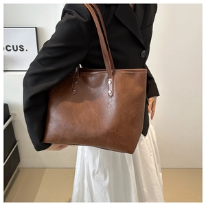 Detailed texture of brown faux leather tote bag with gold rivets and slim shoulder straps