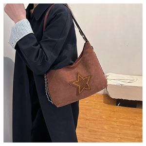 Close-up of brown matte tote bag with star design and chain strap on female model