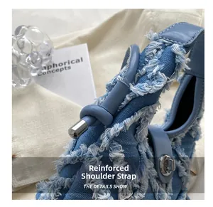 Détail de la bandoulière renforcée sur un sac seau en denim avec garniture à franges