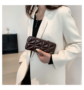 Gros plan d'une pochette en cuir matelassé marron foncé avec motif géométrique et fermoir doré
