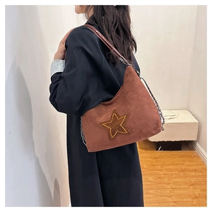Close-up of a brown suede shoulder bag featuring a star embroidery and chain strap detail