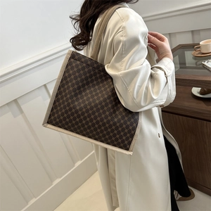 Borsa tote retrò con stampa a quadri e tracolle intrecciate in un interno moderno