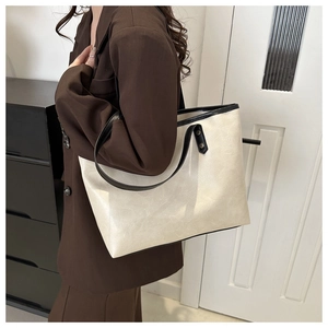 Detail view of cream tote bag with black strap contrast and textured leather finish
