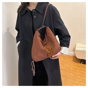 Close-up of brown suede shoulder bag with gold sequin star and metal chain detail