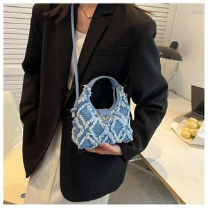 Vue détaillée d'un sac seau en denim bleu avec bords effilochés blancs et fermoir argenté