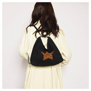 Detail view of a black suede tote bag featuring a vibrant orange star patch decoration