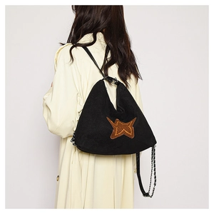 Detail view of black suede moon bag with embroidered star on yellow trench coat