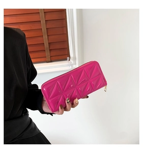 Détail du portefeuille en cuir rose matelassé avec fermeture éclair dorée et losanges
