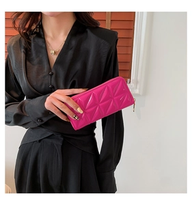 Détail d'une pochette matelassée rose rouge avec coutures géométriques et zip doré