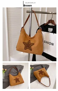 Detail of brown suede tote bag with stitched star patch and decorative metal chain